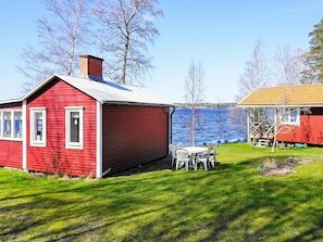A red wooden house with a white door and windows, a small table with chairs, and a wooden deck. - 6 Person Holiday Home in Gullspang-by Traum (Gullspång)