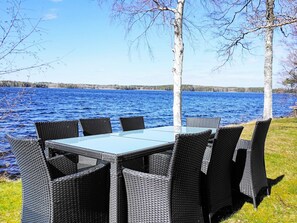 A table and chairs set up by a lakeside with birch trees. - 6 Person Holiday Home in Gullspang (Gullspång)