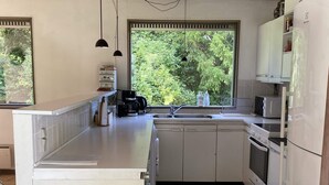 A modern kitchen with white cabinetry, a built-in oven, a microwave, and a coffee maker. - Seaside Retreat in Dronningmolle-by Traum (Dronningmolle)