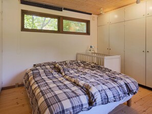 A bedroom with a bed, two windows, a radiator, and a wardrobe.