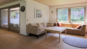 A living room with a beige sofa, a small table, and a large window with a view of greenery. - Seaside Retreat in Dronningmolle-by Traum (Dronningmolle)
