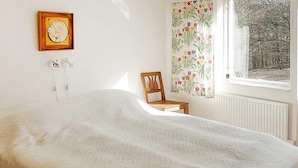 A bedroom with a bed, a chair, a window with curtains, and a wall-mounted picture. - 4 Person Holiday Home in Veberod-by Traum (Veberöd)