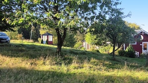 A rural landscape with a red barn, a small wooden structure, and a tree. - 4 Person Holiday Home in Veberod-by Traum (Veberöd)