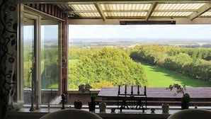 A room with a large window overlooking a green landscape, a wooden ceiling, and two chairs with cushions. - 4 Person Holiday Home in Veberod-by Traum (Veberöd)