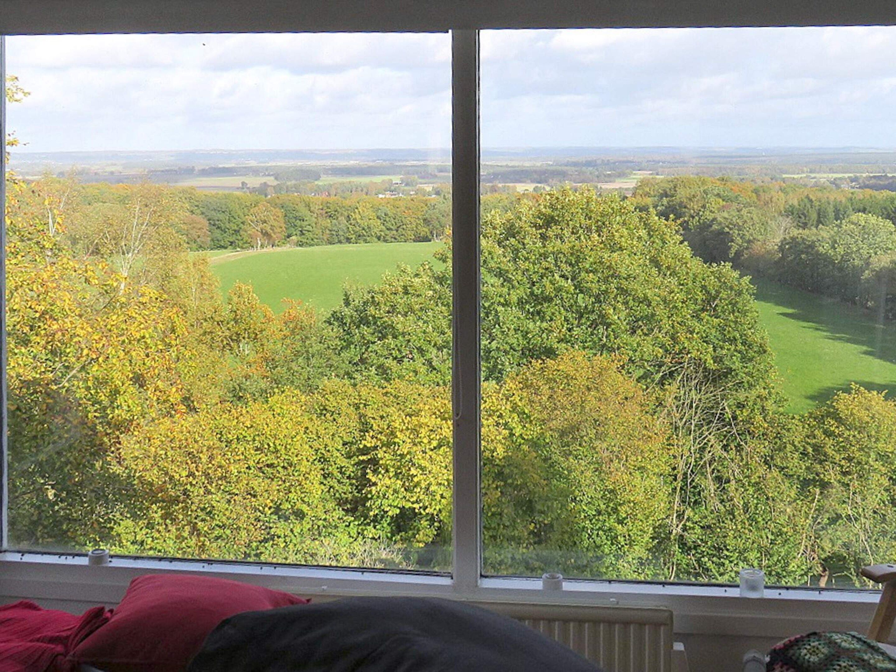 A room with a large window overlooking a green landscape with trees and a golf course.
