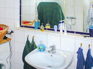 A bathroom with a white sink, a mirror above it, and a towel hanging on the wall. - 4 Person Holiday Home in Veberod (Veberöd)