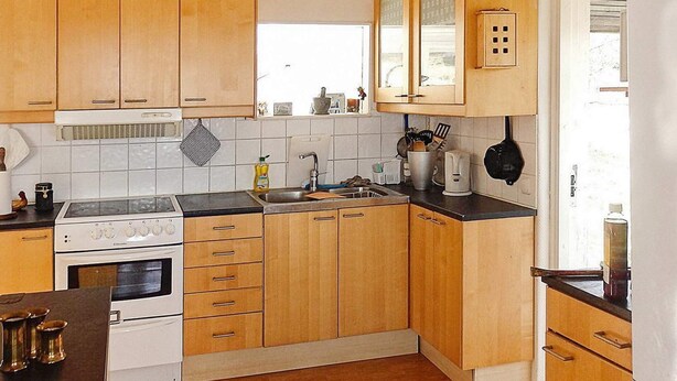 A kitchen with wooden cabinets, a stove, a sink, and various kitchen items. - 4 Person Holiday Home in Veberod-by Traum (Veberöd)