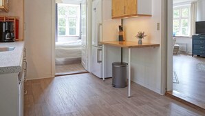 A modern kitchen with wooden cabinets, a built-in oven, and a small island with a sink. - 10 Person Holiday Home in Nexo (Nexø)