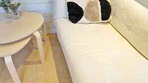 A white sofa with a textured rug, a round table with glassware, and a wall with horizontal lines. - 4 Person Holiday Home in Grisslehamn (Grisslehamn)