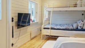 A bunk bed room with a TV mounted on the wall, wooden flooring, and a window with a view. - 4 Person Holiday Home in Grisslehamn (Grisslehamn)