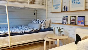 A bunk bed with a patterned bedspread, a small round table with a vase, and a couch with a pillow. - 4 Person Holiday Home in Grisslehamn (Grisslehamn)