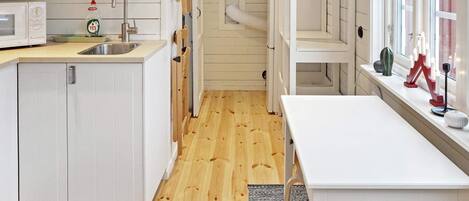 A compact kitchen with white cabinetry, a microwave, a sink, and a window with a view.