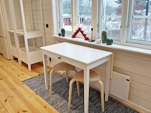 A white desk with a chair, a window with a view of trees, and a shelf with decorative items. - 4 Person Holiday Home in Grisslehamn-by Traum (Grisslehamn)