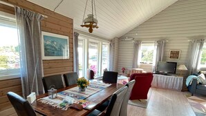 A cozy cabin interior with a wooden dining table, chairs, a TV, and a sofa. - 4 Star Holiday Home in Espevaer (Bomlo)