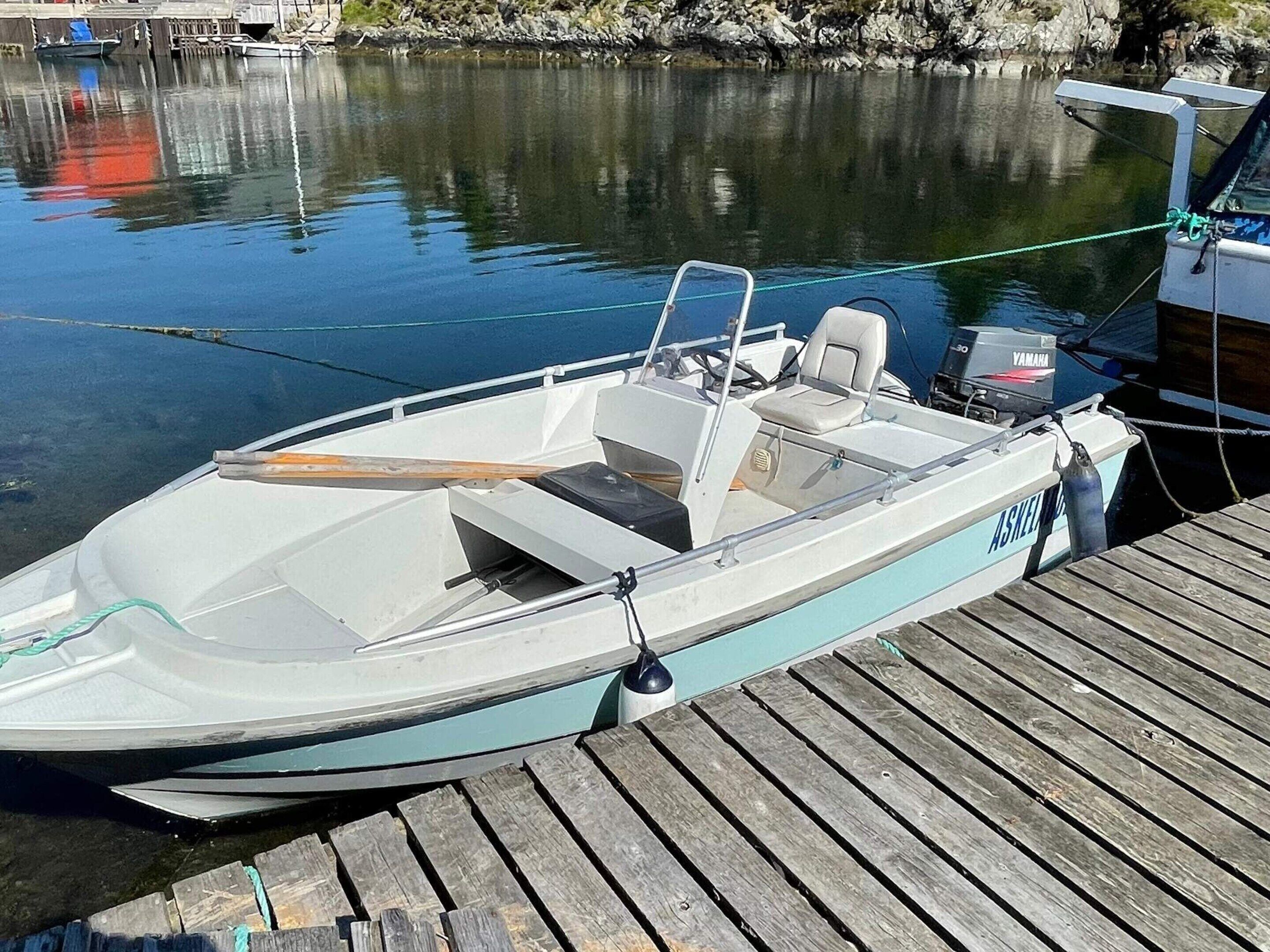 A small motorboat docked at a wooden pier.