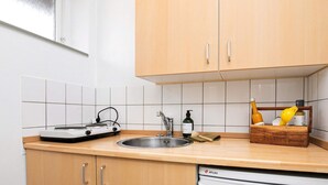 Eine Küche mit Holzausstattung, einer Edelstahlspüle, einem weißen Geschirrspüler und einem tragbaren Gasherd.