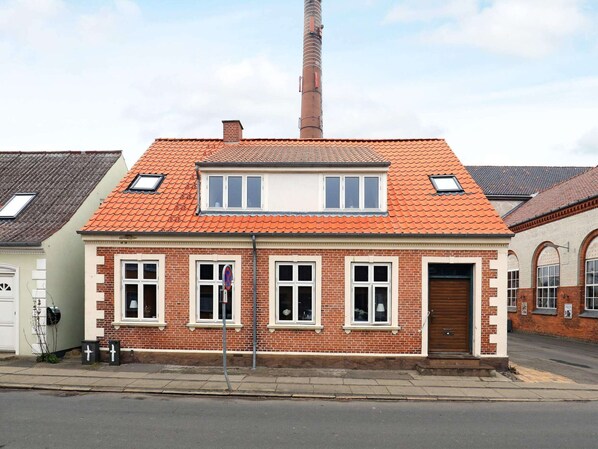 A two-story brick house with a red-tiled roof, a chimney, and a garage door.