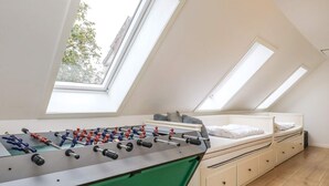 Une pièce avec une table de baby-foot, un lit et des fenêtres de toit.