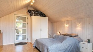 A bedroom with a bed, a wardrobe, a nightstand, and a lamp.