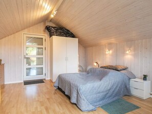 A bedroom with a bed, a wardrobe, a nightstand, and a lamp.