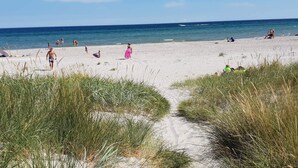 A sandy beach with people walking and sitting, a clear sky, and the ocean in the background. - 4 Star Holiday Home in Hals (Hals)