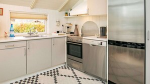 A modern kitchen with white cabinets, a stainless steel refrigerator, a Bosch oven, and a checkered floor.