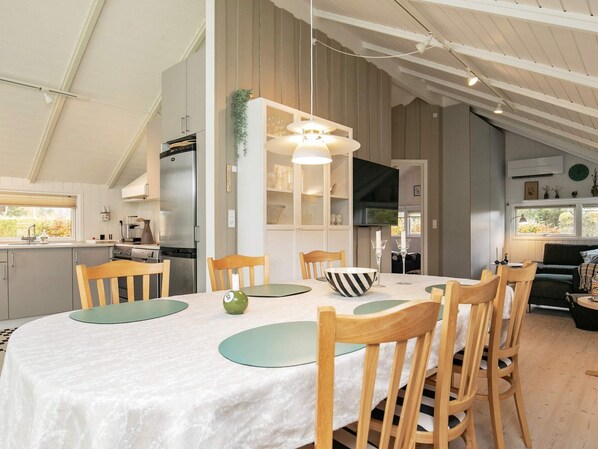 A modern kitchen with a dining area, featuring a large table, chairs, and a hanging light fixture.