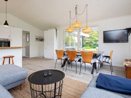 A modern living room with a sofa, a round coffee table, and a dining area with chairs and a table.