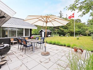An outdoor patio with a table and chairs, a grill, and a flag.