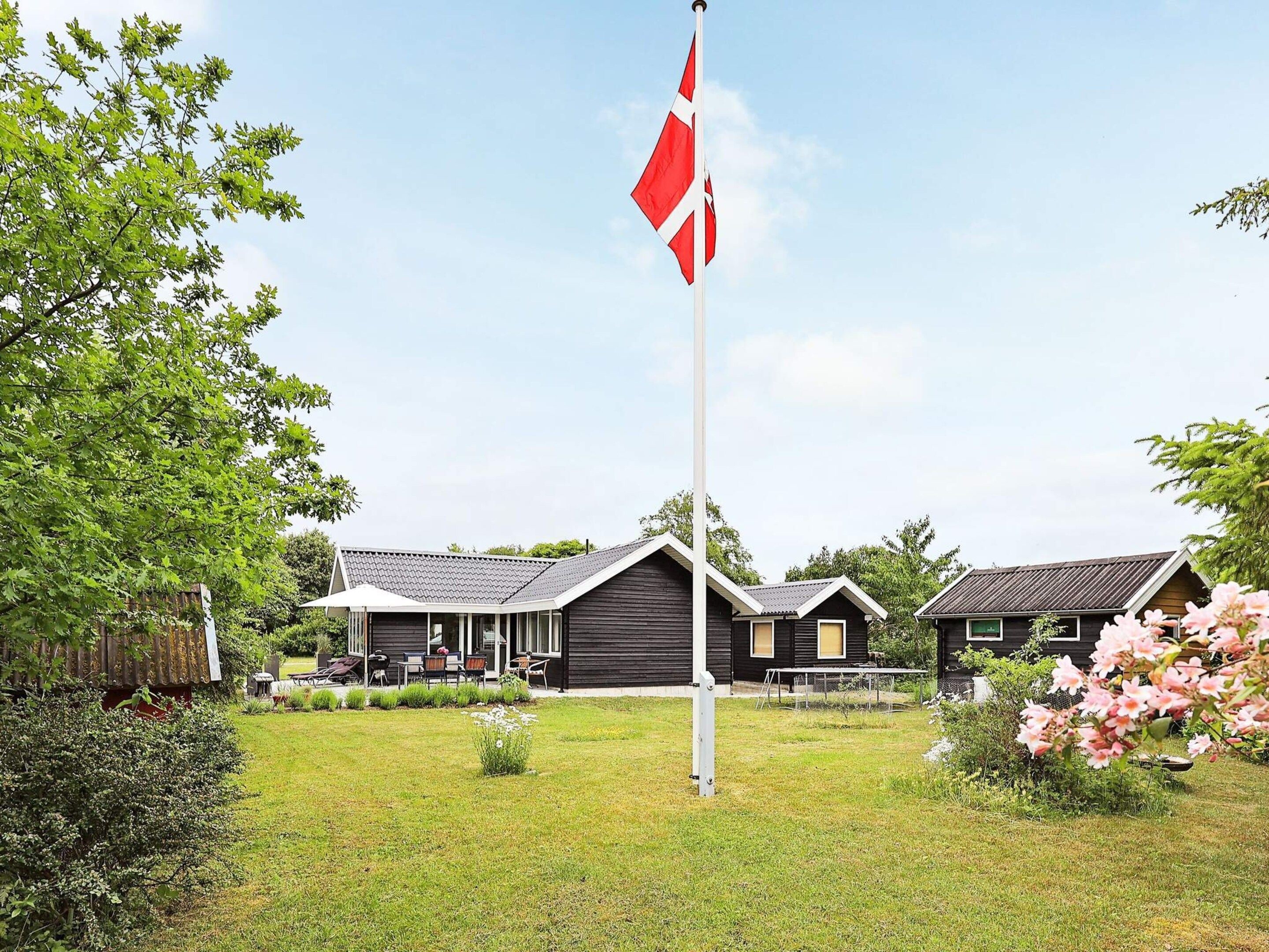 A residential area with a flagpole, two houses, and a well-maintained lawn.