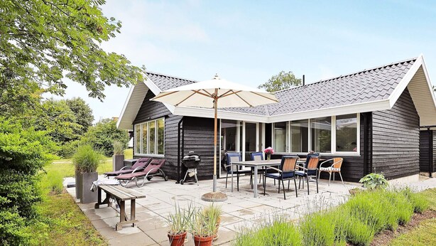 A modern house with a covered patio, outdoor furniture, and a grill. - 4 Star Holiday Home in Karrebaeksminde (Karrebæksminde)