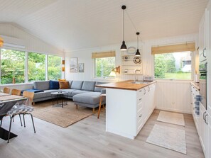 A modern kitchen with white cabinetry, a central island, and a dining area with a sofa and chairs.