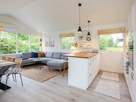 Una cocina moderna con armarios blancos, una isla central y un comedor con sofá y sillas.