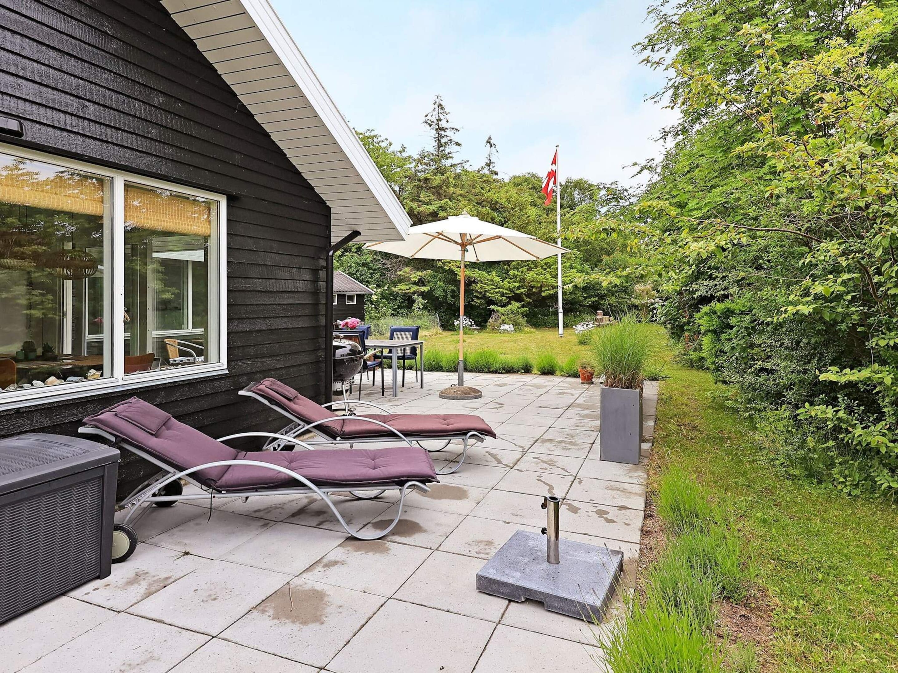 A patio with lounge chairs, a grill, and a flag.