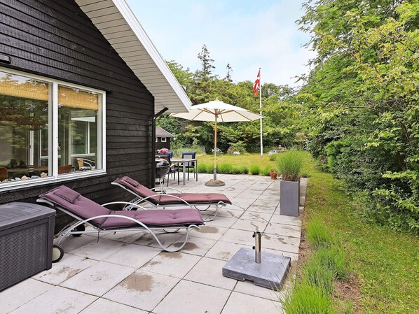 A patio with lounge chairs, a grill, and a flag.