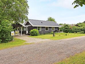 A two-story house with a gravel driveway and a covered porch.