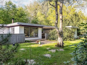 A modern house with a large window, a deck, and a small shed in a wooded area. - 6 Person Holiday Home in Hadsund (Hadsund)