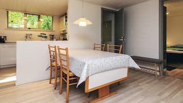 A modern kitchen with wooden cabinets, a dining table with chairs, and a pendant light.