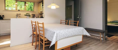 A modern kitchen with wooden cabinets, a dining table with chairs, and a pendant light.