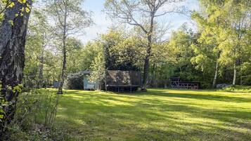 A grassy outdoor area with trees, a small shed, and a covered structure.