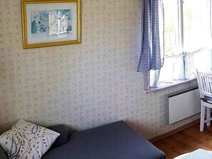 A room with a bed, a chair, a radiator, and a window with curtains. - 4 Person Holiday Home in Kristianstad (Kristianstad)
