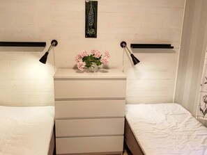 A bedroom with a white dresser, two bedside lamps, and a small potted plant on the dresser.