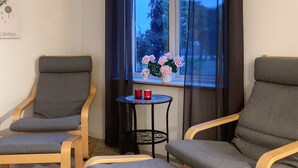 Huoneessa on kaksi nojatuolia, pieni pyöreä pöytä ja penkki.