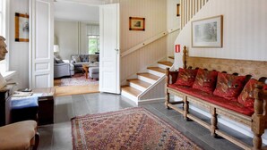 Ein geräumiges Wohnzimmer mit einem roten Sofa, einem gemusterten Teppich und einer Treppe, die in einen weiteren Raum führt.