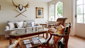 Ein Wohnzimmer mit einer Couch, einem Sessel, einem Couchtisch und einem Wandbild eines Rehs.
