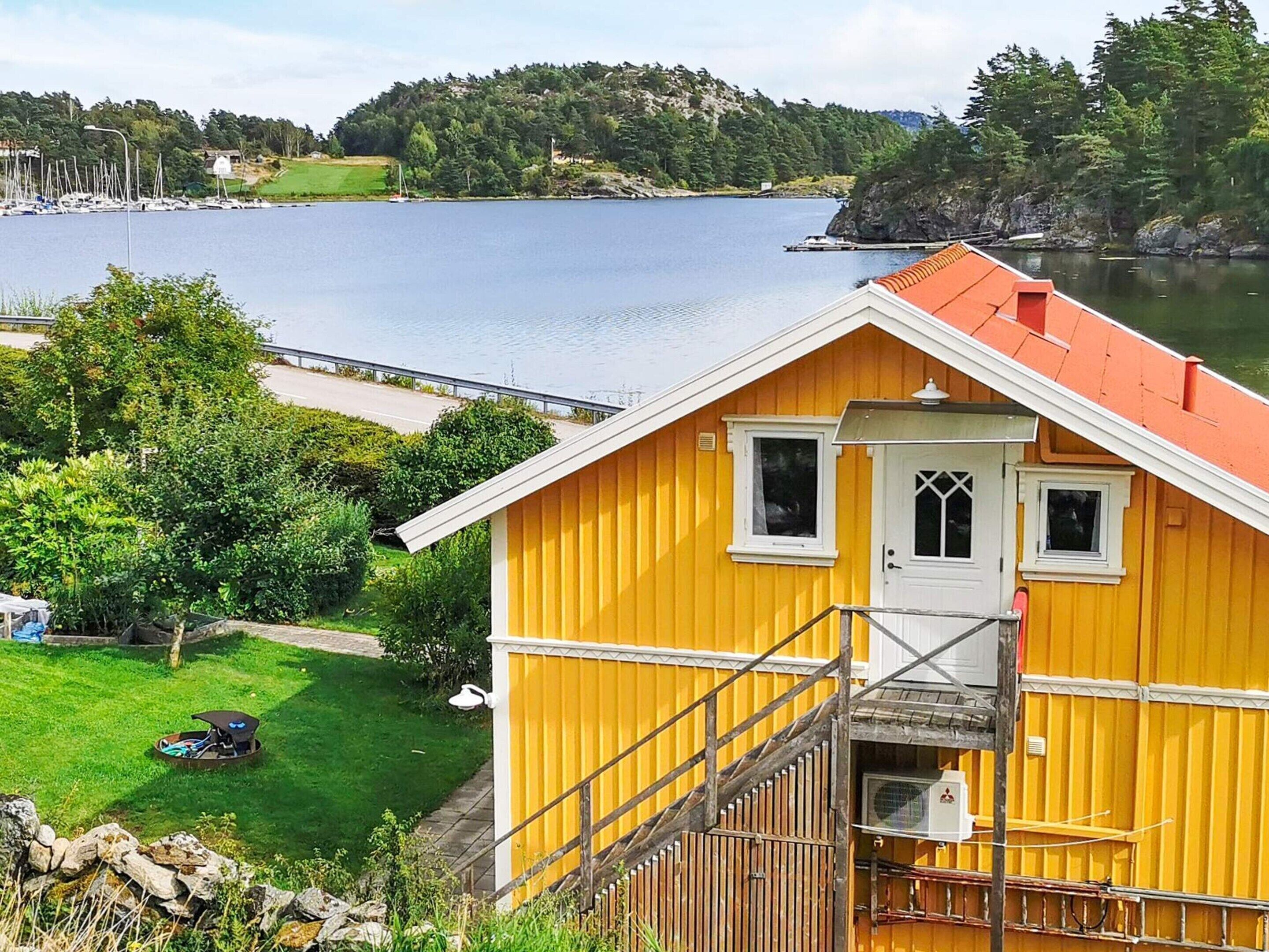 A yellow house with a red roof, a small porch, and a staircase leading to a door.