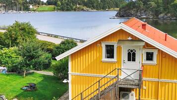 A yellow house with a red roof, a small porch, and a staircase leading to a door.