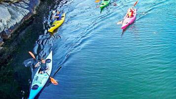 A group of kayaks on calm water near a rocky shoreline.