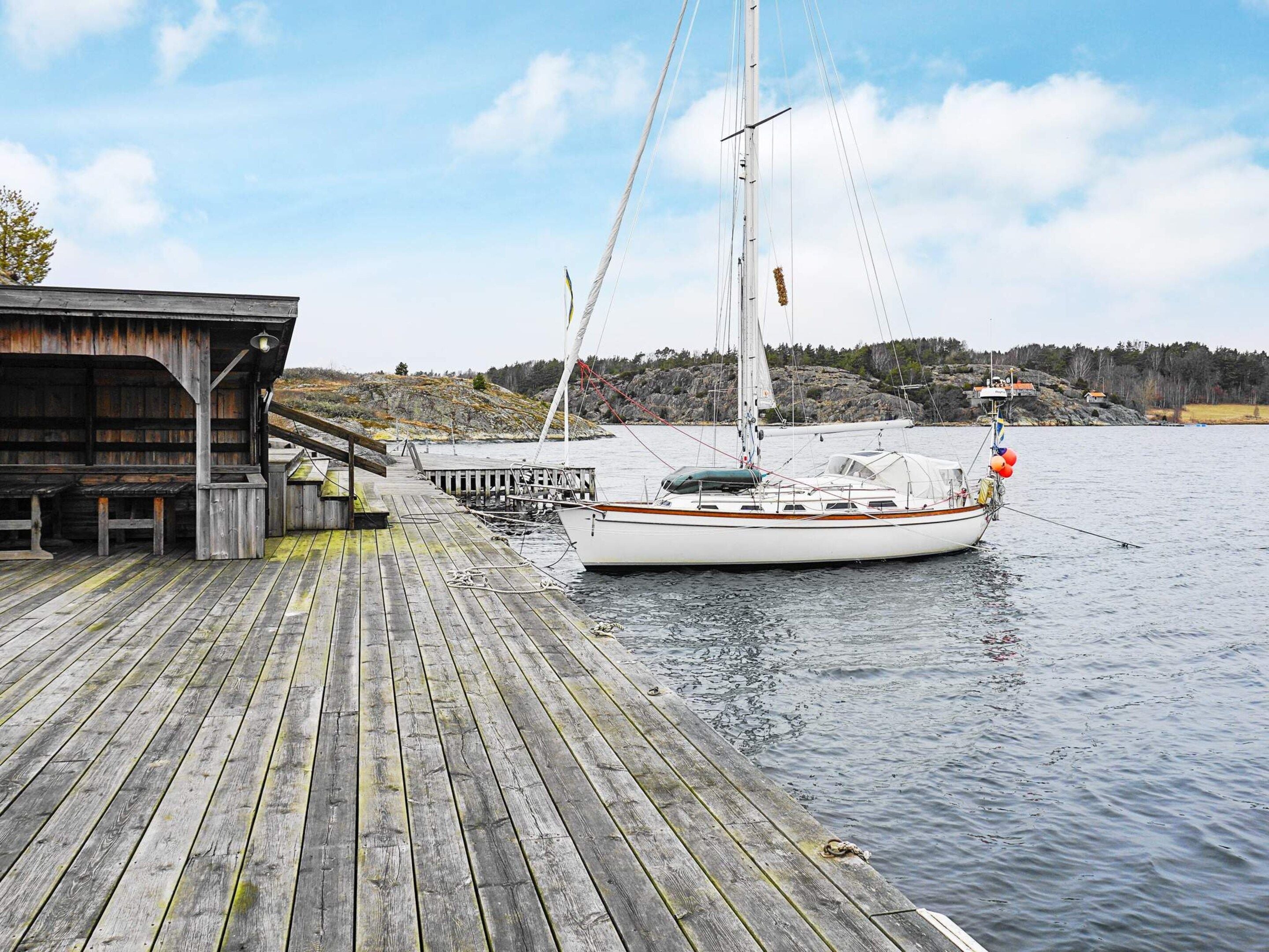 A wooden dock with a sailboat moored at the end.