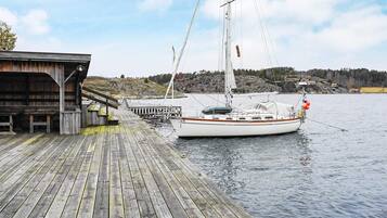 A wooden dock with a sailboat moored at the end.
